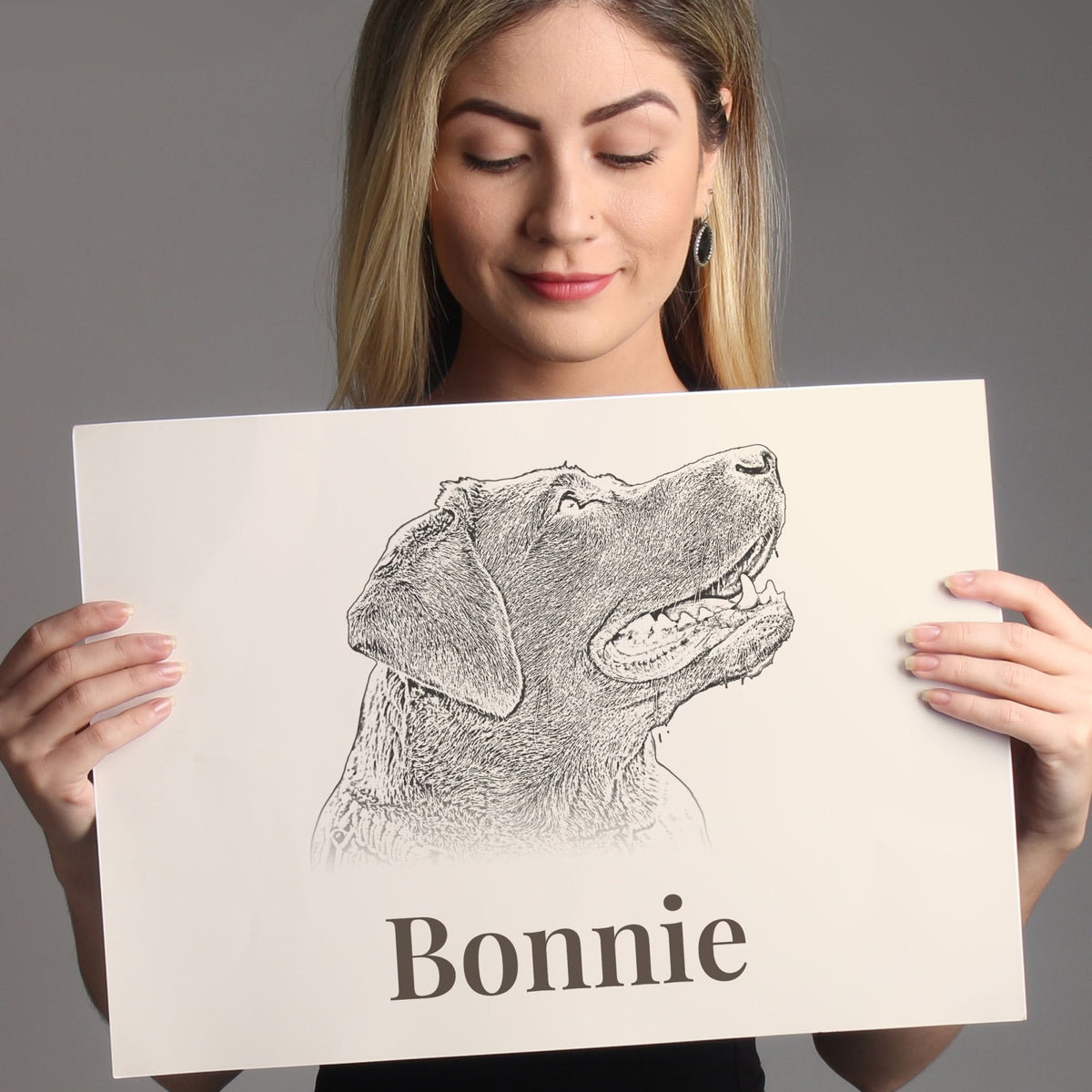 Woman holding an unframed A4 pencil-style dog portrait print with the name Bonnie