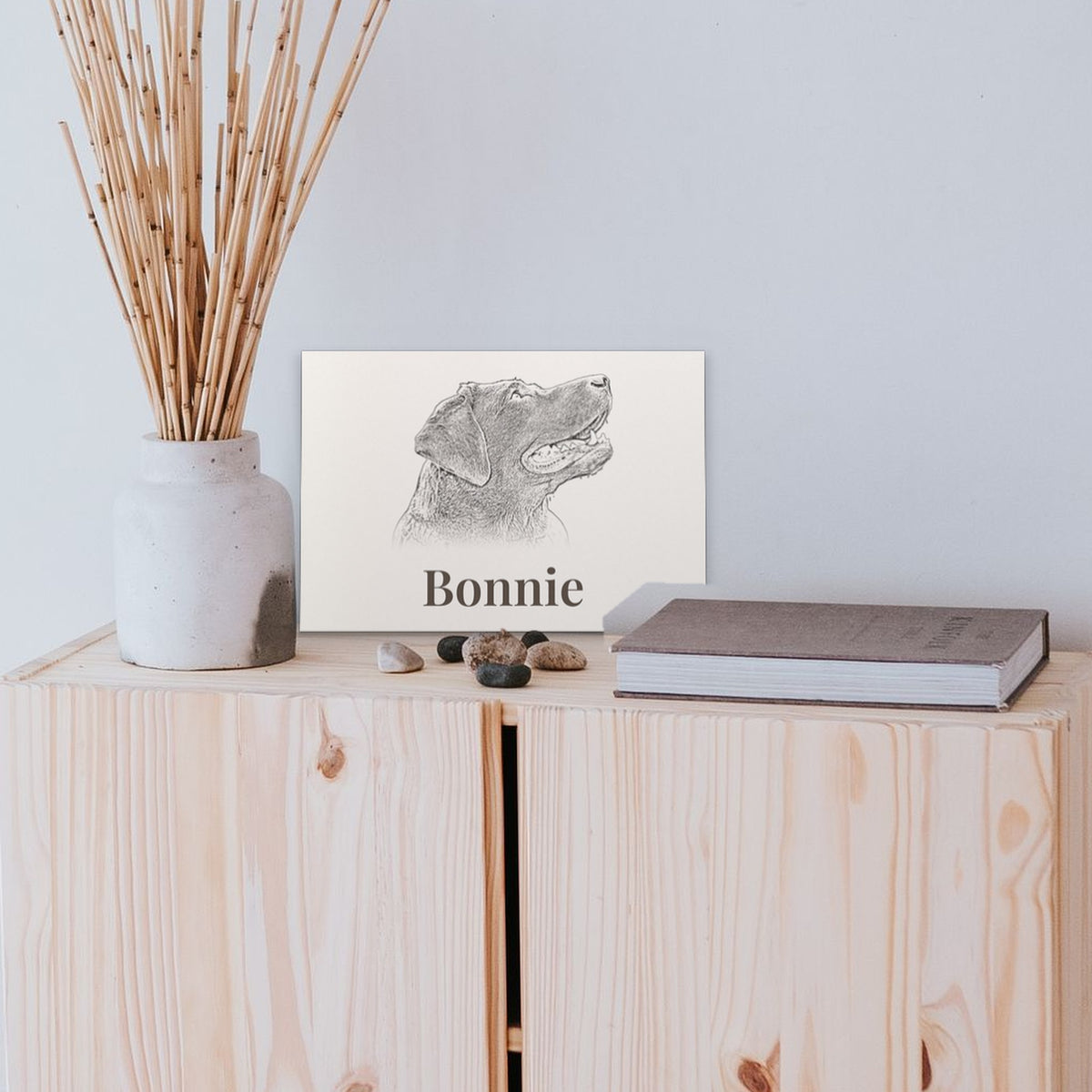 Personalised A4 pet portrait print propped on a wooden cabinet